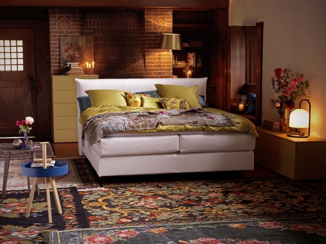 suaugusiųjų kambario apdaila suaugusiųjų miegamasis-romantiškas-stalinis šviestuvas-elegantiškas kilimas-raštai-spalvos-pagalvėlės-šilta-geltona-maža-žvakidė-vaza-gėlės