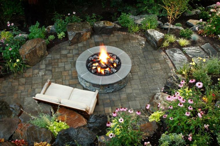屋外のトレンディなスペースのソファのクッションを造園するための屋外の暖炉の丸い石のアイデア