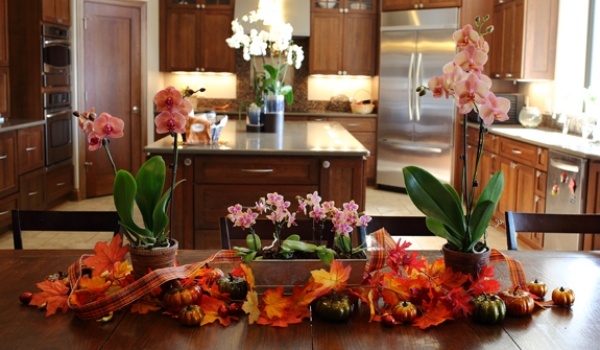 Valgomojo stalo kompozicija dekoruotos orchidėjos palieka rudenį